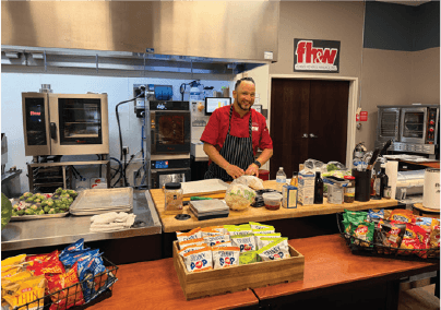 Chef presenting food in a professional commercial kitchen at an FHW event